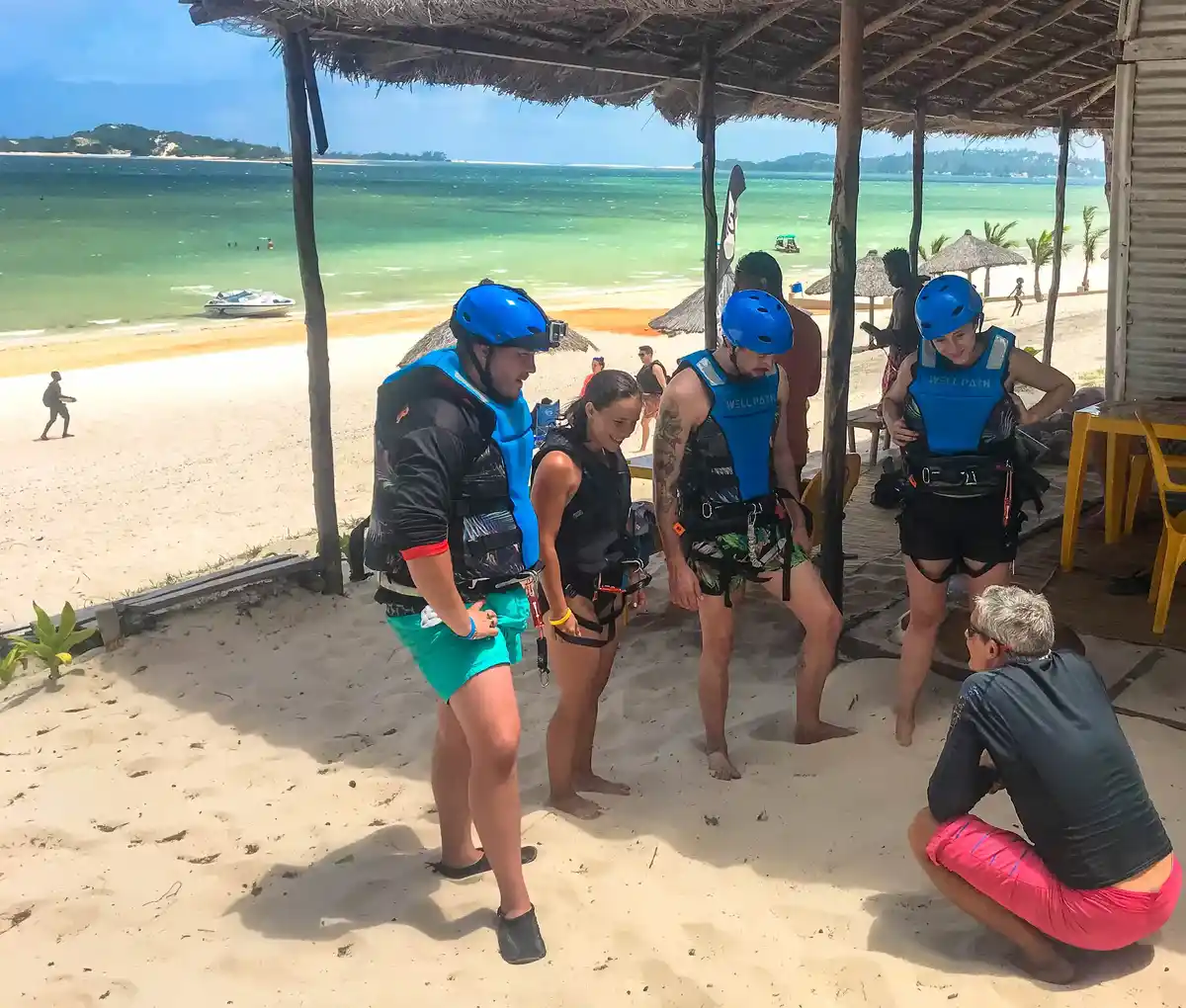 Groupe d'élèves en casque et gilet pendant le briefing sur la plage, face au lagon de Bilene