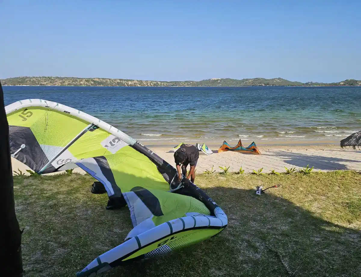 Membre de l'équipe du centre gonflant une aile de kite sur la pelouse, face au lagon